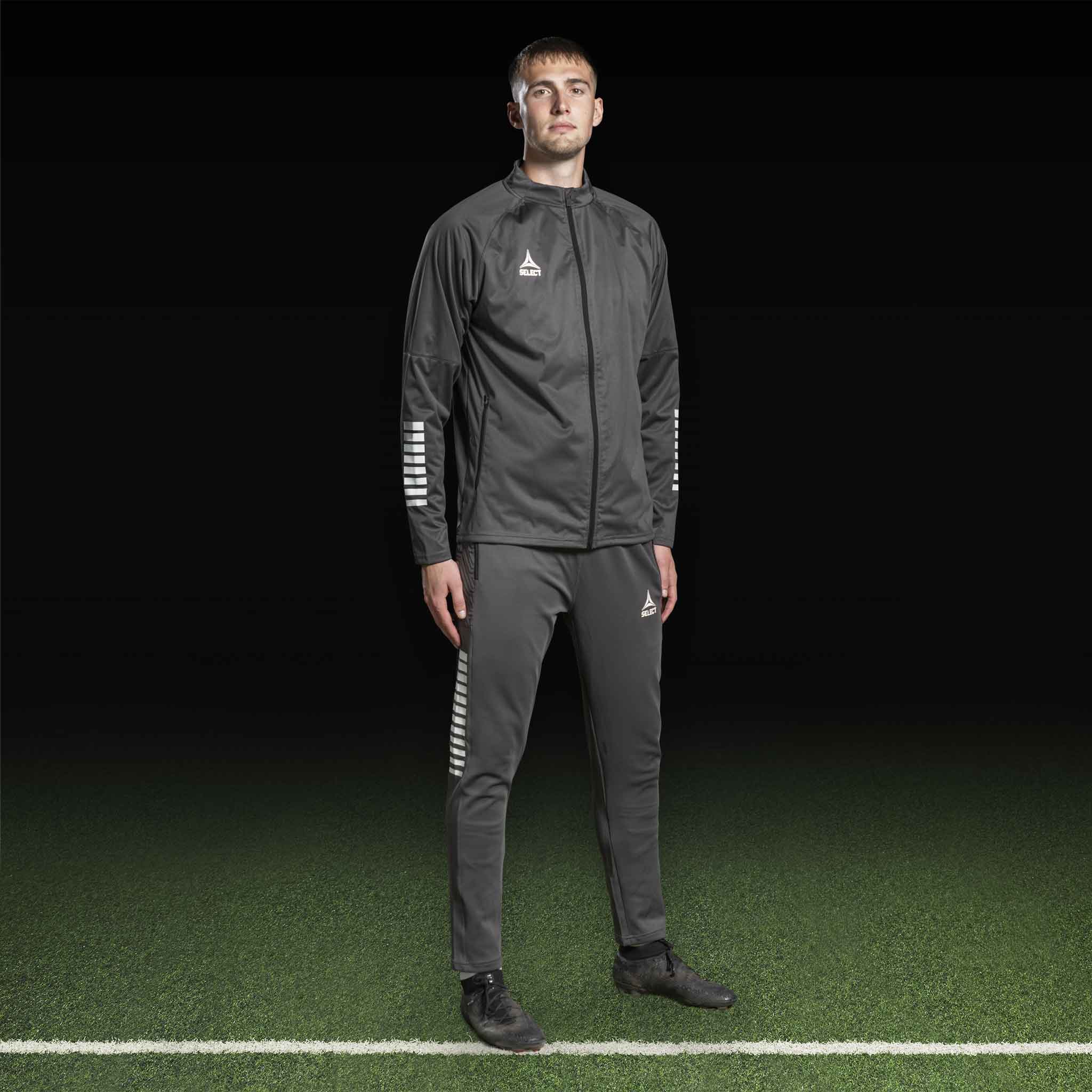 Mandlig fodboldspiller i grå og hvid Training jacket Monaco v24, Match & Training wear, forfra på banen.