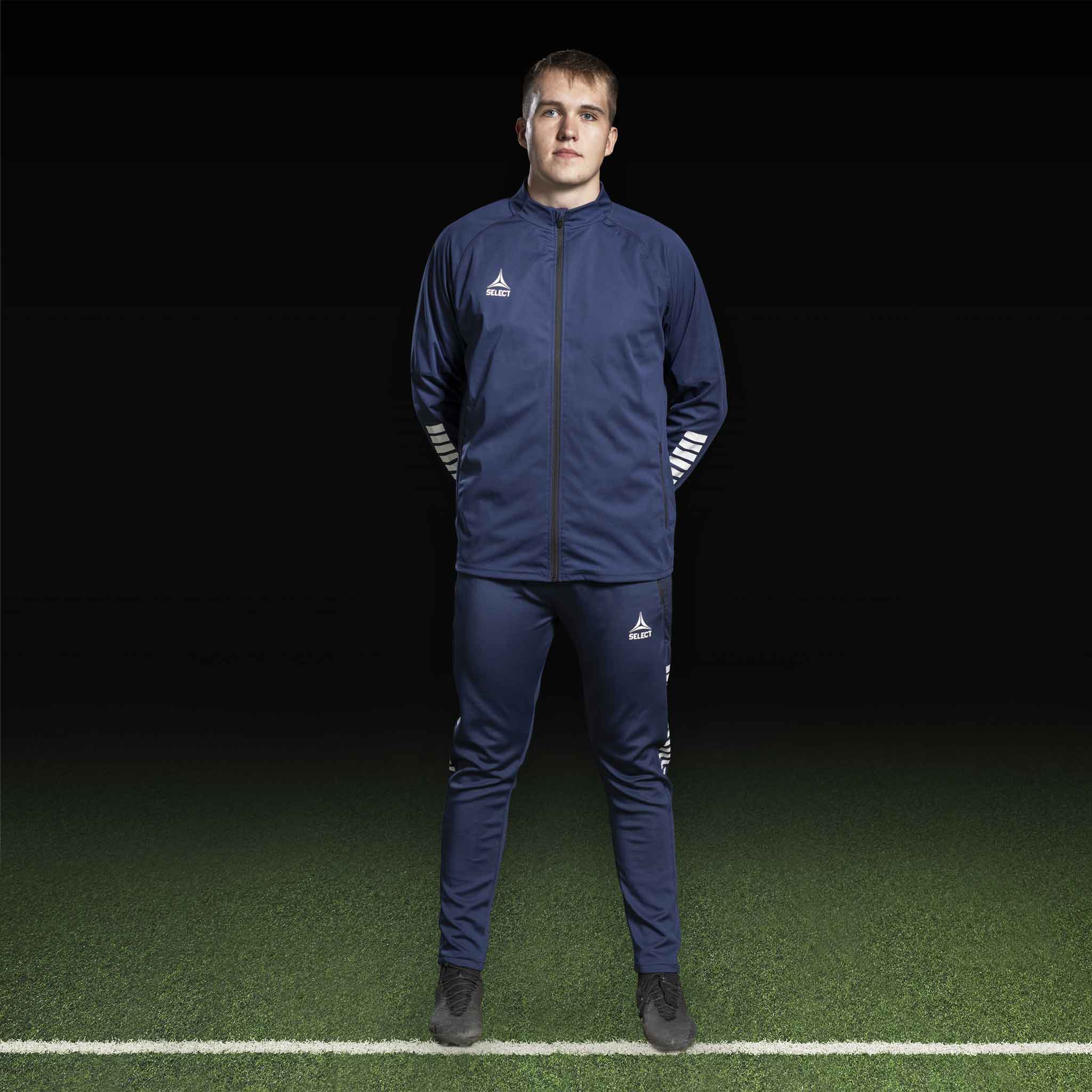 Mandlig fodboldspiller i navy Training jacket Monaco v24, Match & Training wear, med hvidt logo, forfra på banen.