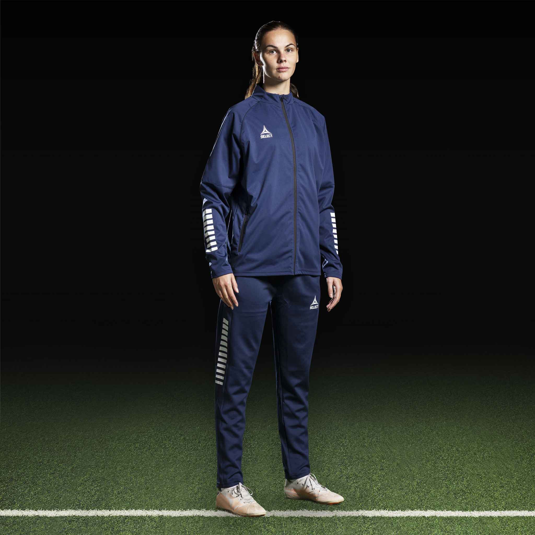 Kvindelig fodboldspiller i marineblå og hvid Training jacket Monaco v24, Match & Training wear, set forfra.