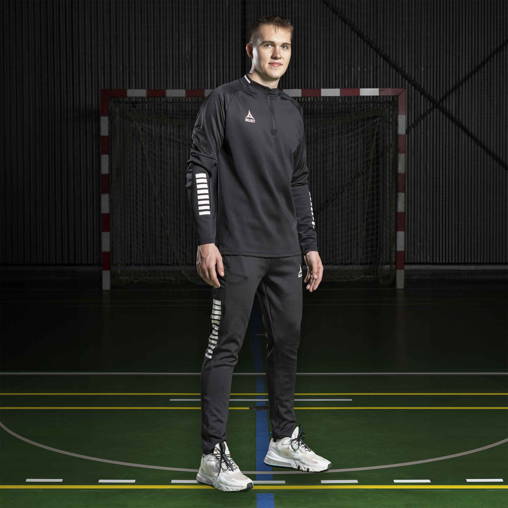 Mandlig håndboldspiller i sort Training sweat 1/2 zip Monaco v24, Match & Training wear, på banen.