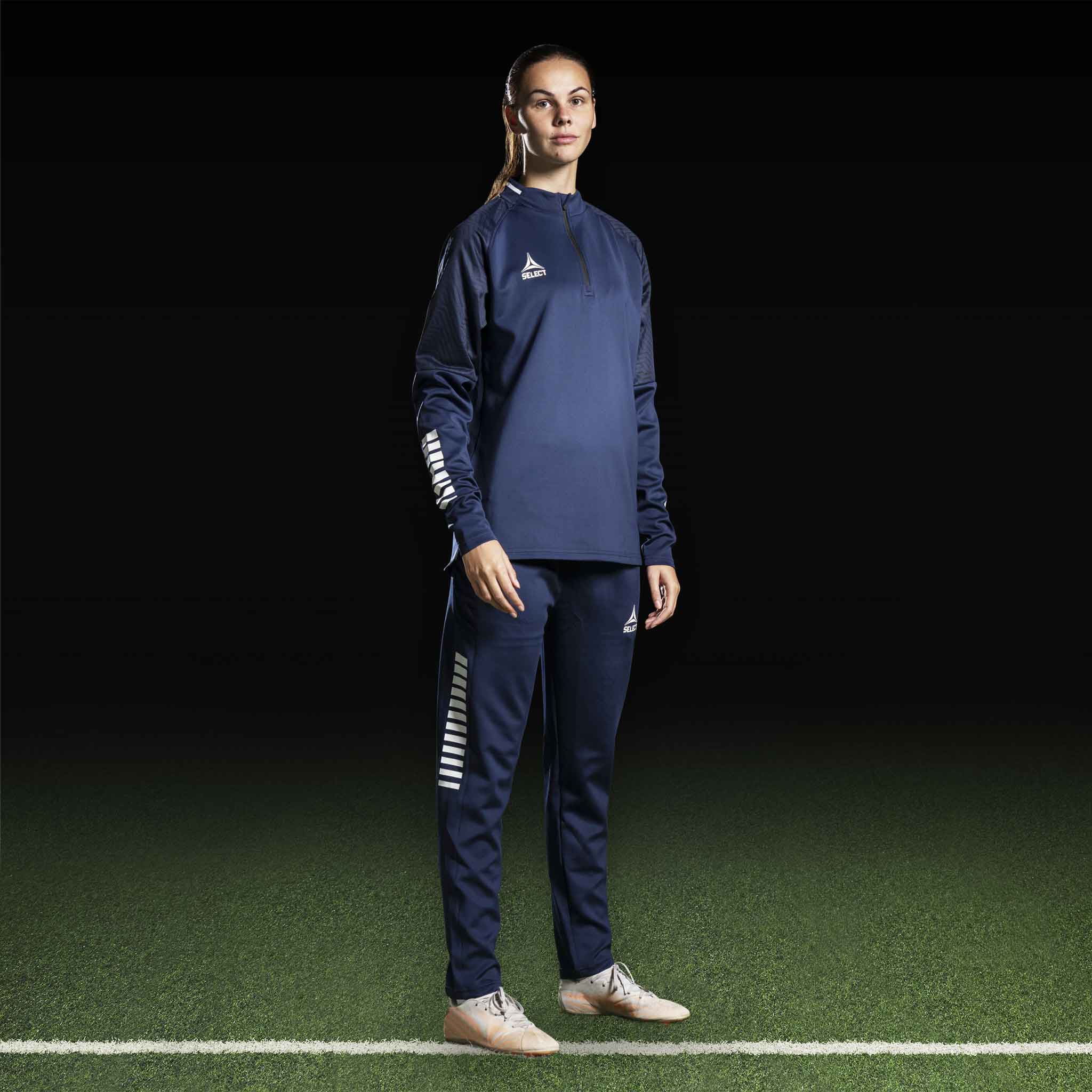 Kvindelig fodboldspiller i navy Training sweat 1/2 zip Monaco v24, Match & Training wear, med hvide detaljer, forfra.