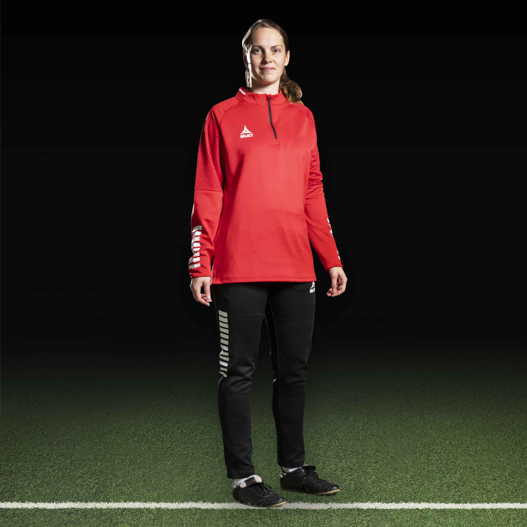 Kvindelig fodboldspiller i rød Training sweat 1/2 zip Monaco v24 og sorte bukser, Match & Training wear.