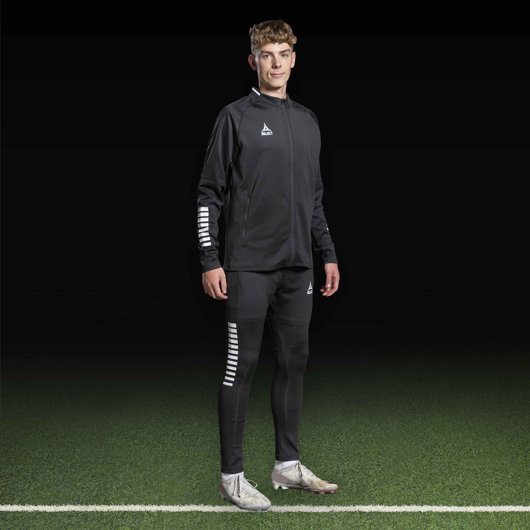 Mandlig fodboldspiller i sort-hvid Zip jacket Monaco v24, Match & Training wear, set forfra på banen.