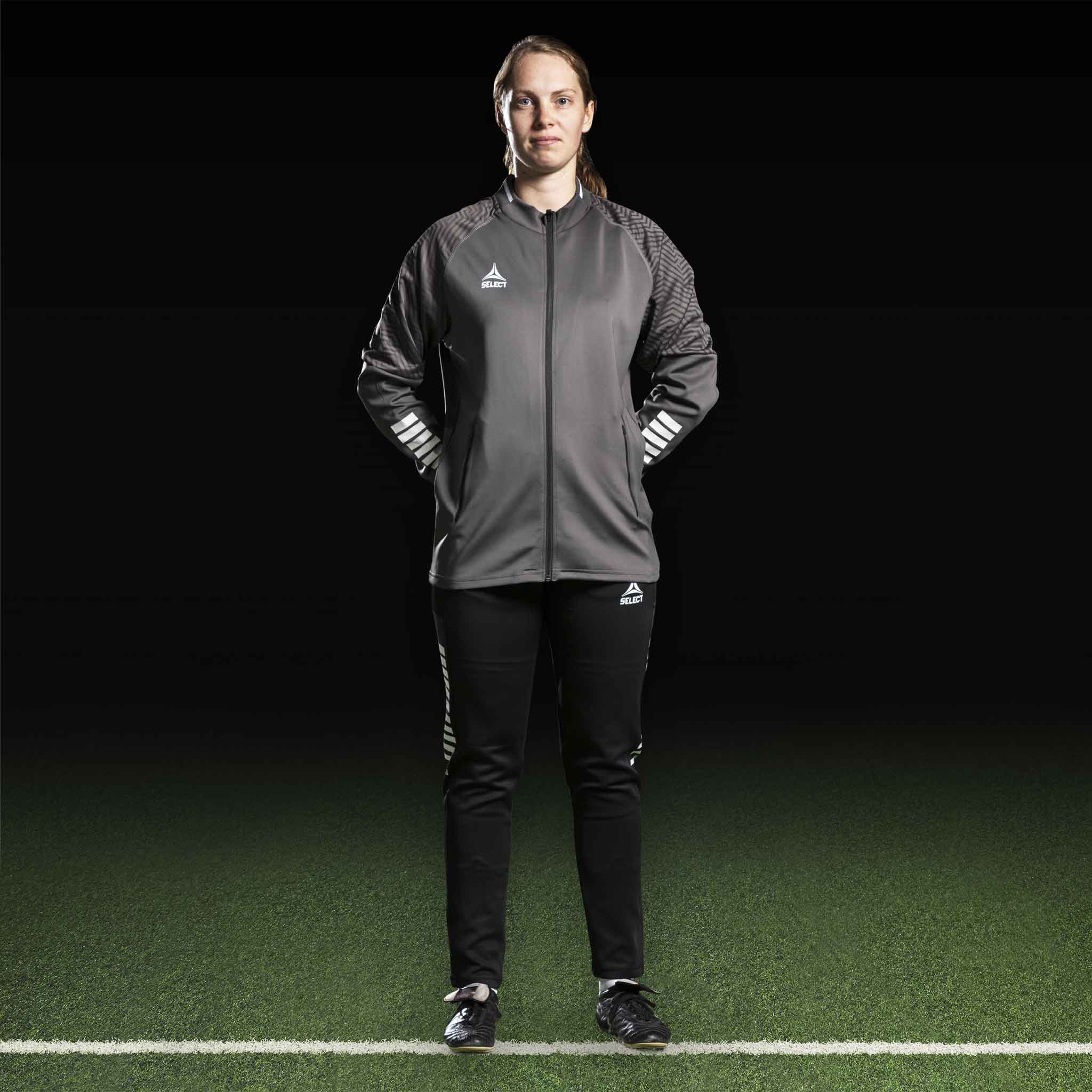 Kvindelig fodboldspiller i grå Zip jacket Monaco v24 og sorte bukser, Match & Training wear, forfra.