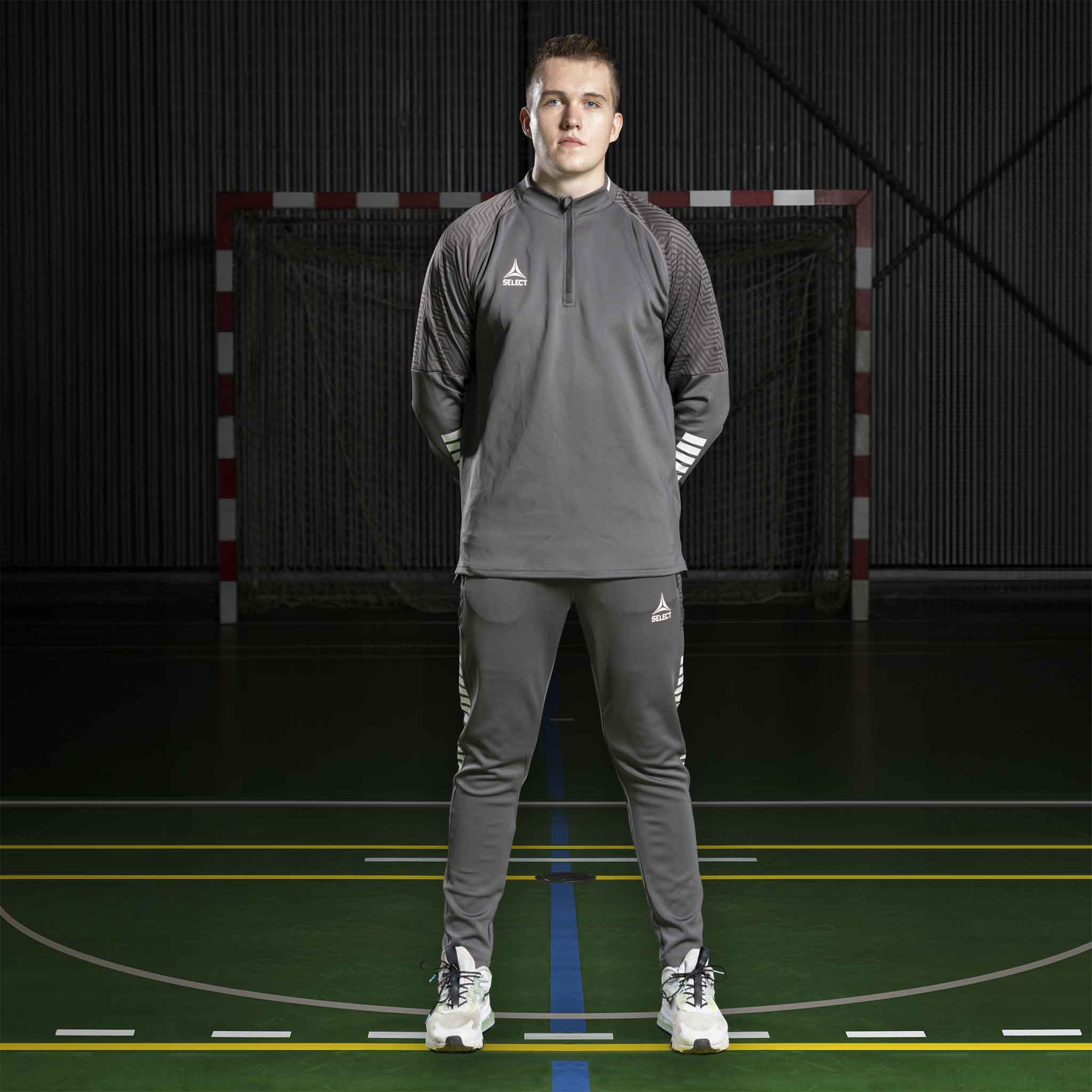 Mandlig fodboldspiller i grå Zip jacket Monaco v24 og matchende bukser, Match & Training tøj, forfra på indendørs bane.