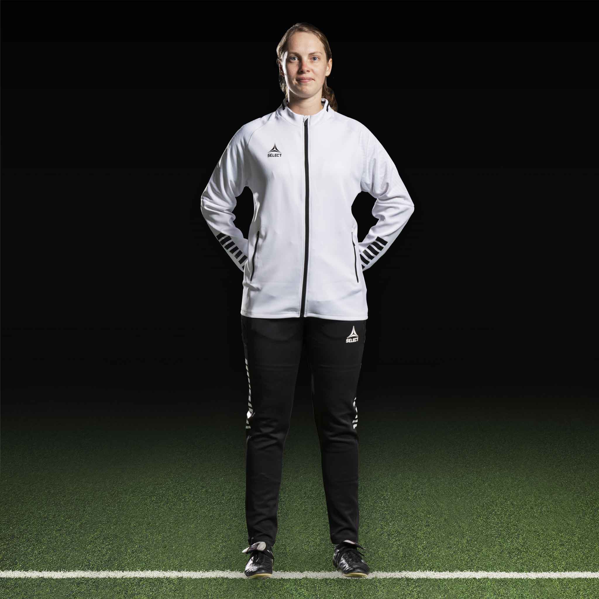 Kvindelig fodboldspiller i hvid Zip jacket Monaco v24 og sorte bukser, Match & Training wear, set forfra.