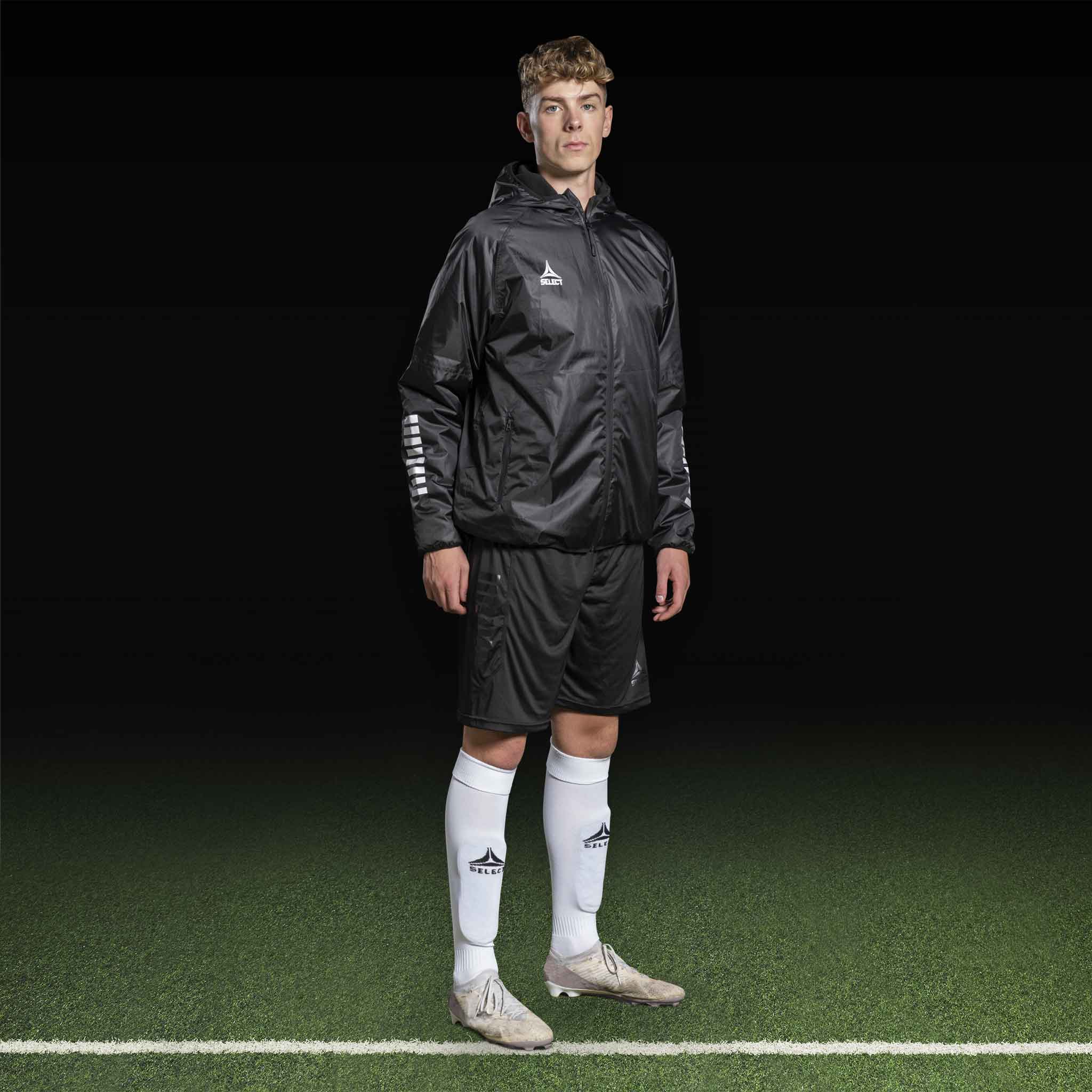 Mandlig fodboldspiller i sorte Player shorts Monaco v24 og jakke, Match & Training wear, set forfra på banen.