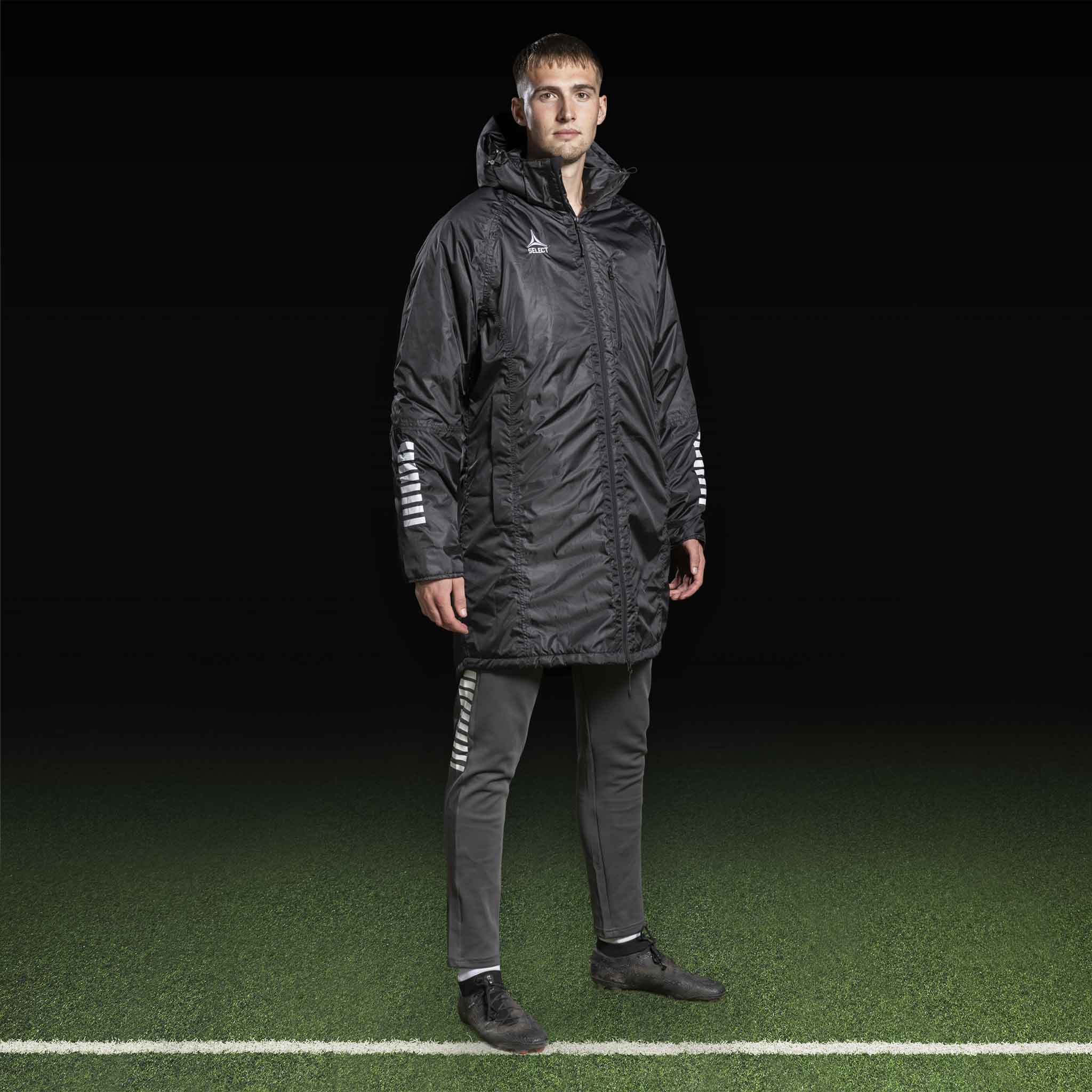 Mandlig fodboldspiller i sort Coach jacket Monaco v24 med grå bukser, Match & Training tøj.