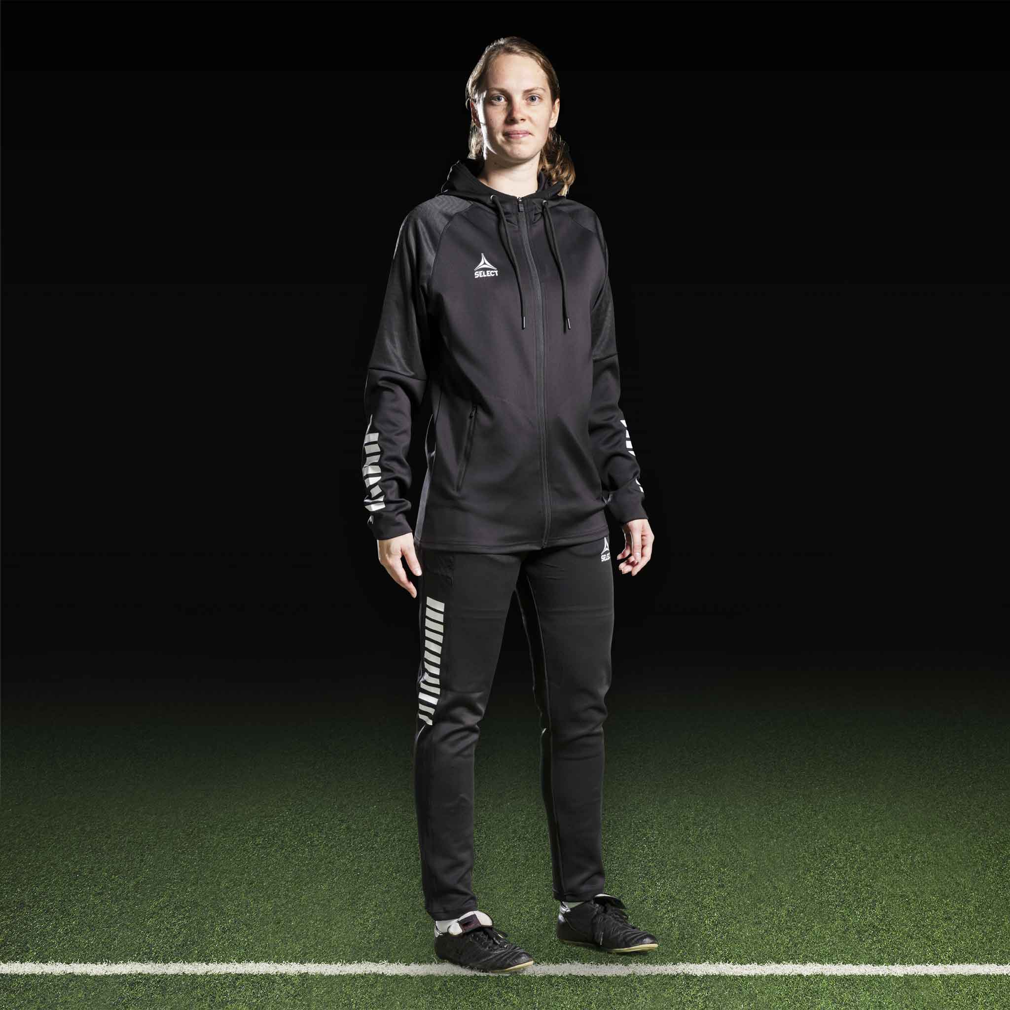 Kvindelig fodboldspiller i sort-hvid Zip hoodie Monaco v24, Match & Training wear, forfra på banen.