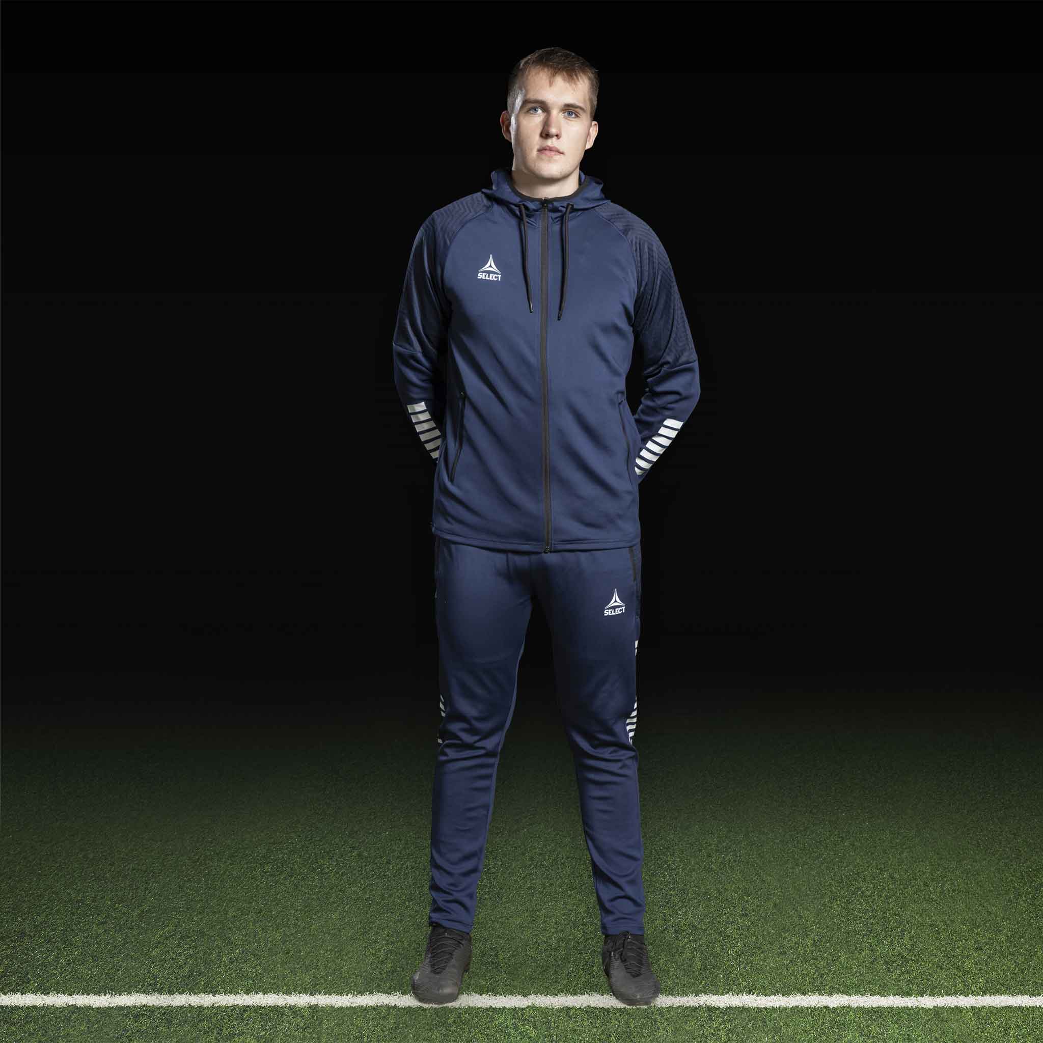 Mandlig fodboldspiller i marineblå og hvid Zip hoodie Monaco v24, Match & Training wear, set forfra.