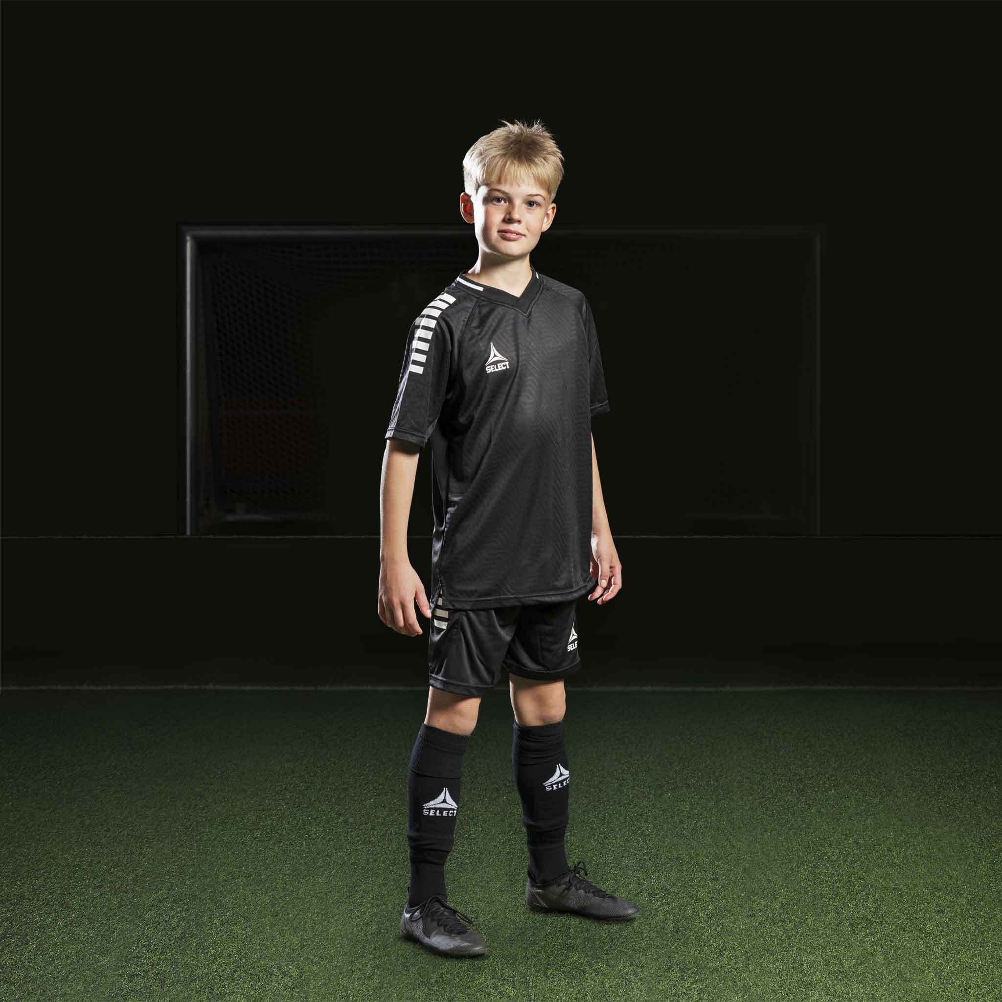 Dreng fodboldspiller i sorte Player shorts Monaco v24, Match & Training wear, med matchende trøje og strømper.