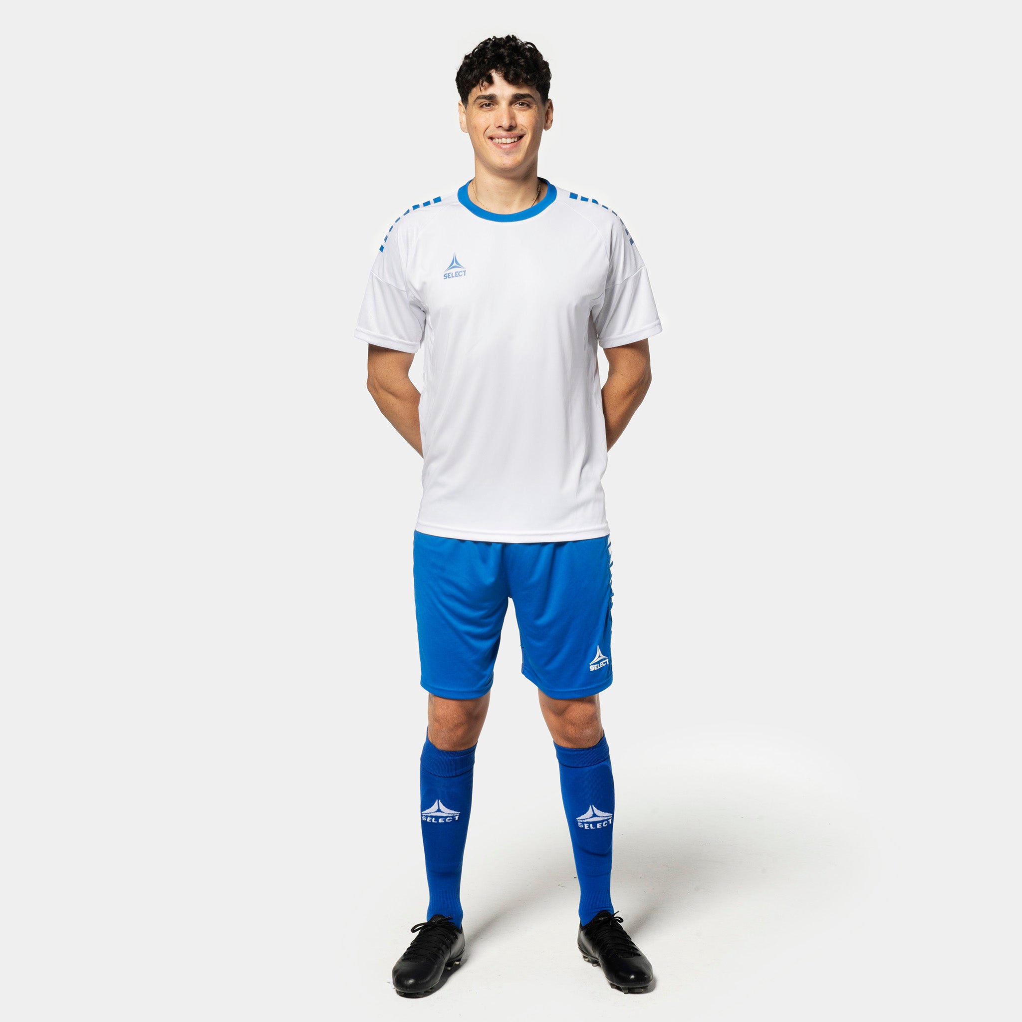 Mandlig fodboldspiller i hvid trøje og blå Player shorts Spain v25, Match & Training wear, set forfra.