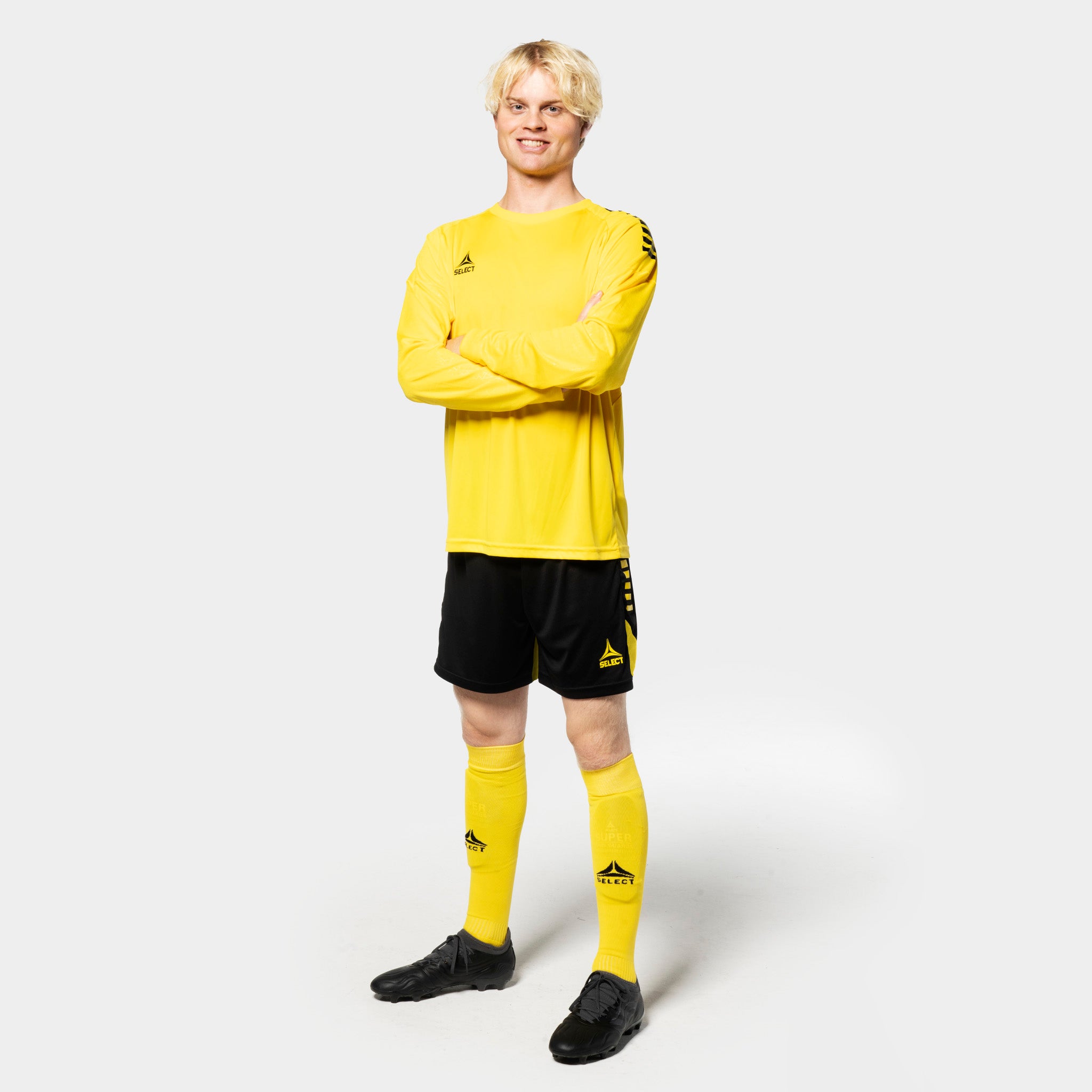 Mandlig fodboldspiller i gul Player shirt L/S Spain v25, sorte shorts, gule strømper. Match & Training wear, forfra.