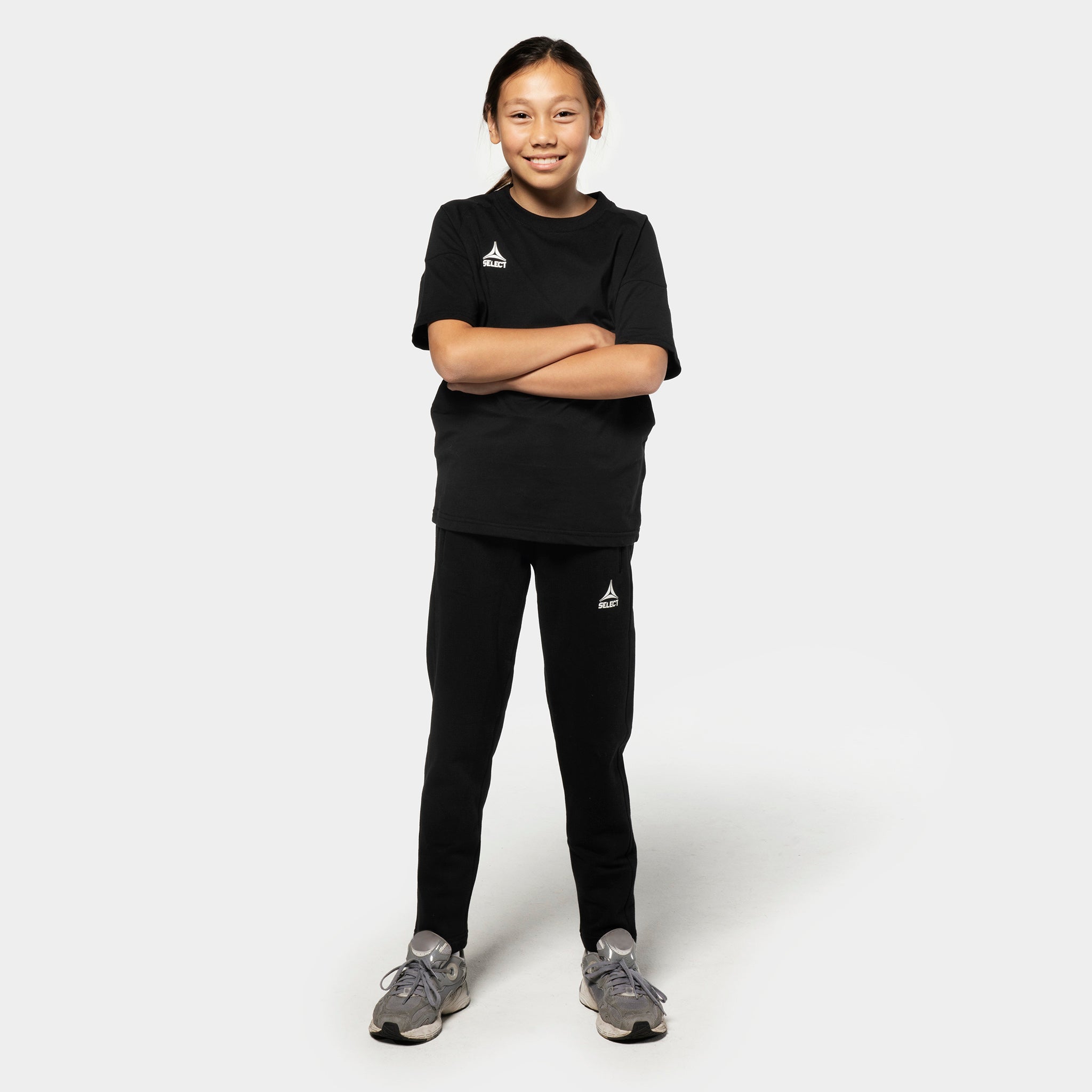 Pige fodboldspiller i sorte Sweat pants Oxford v25 og t-shirt, fritidstøj, set forfra.