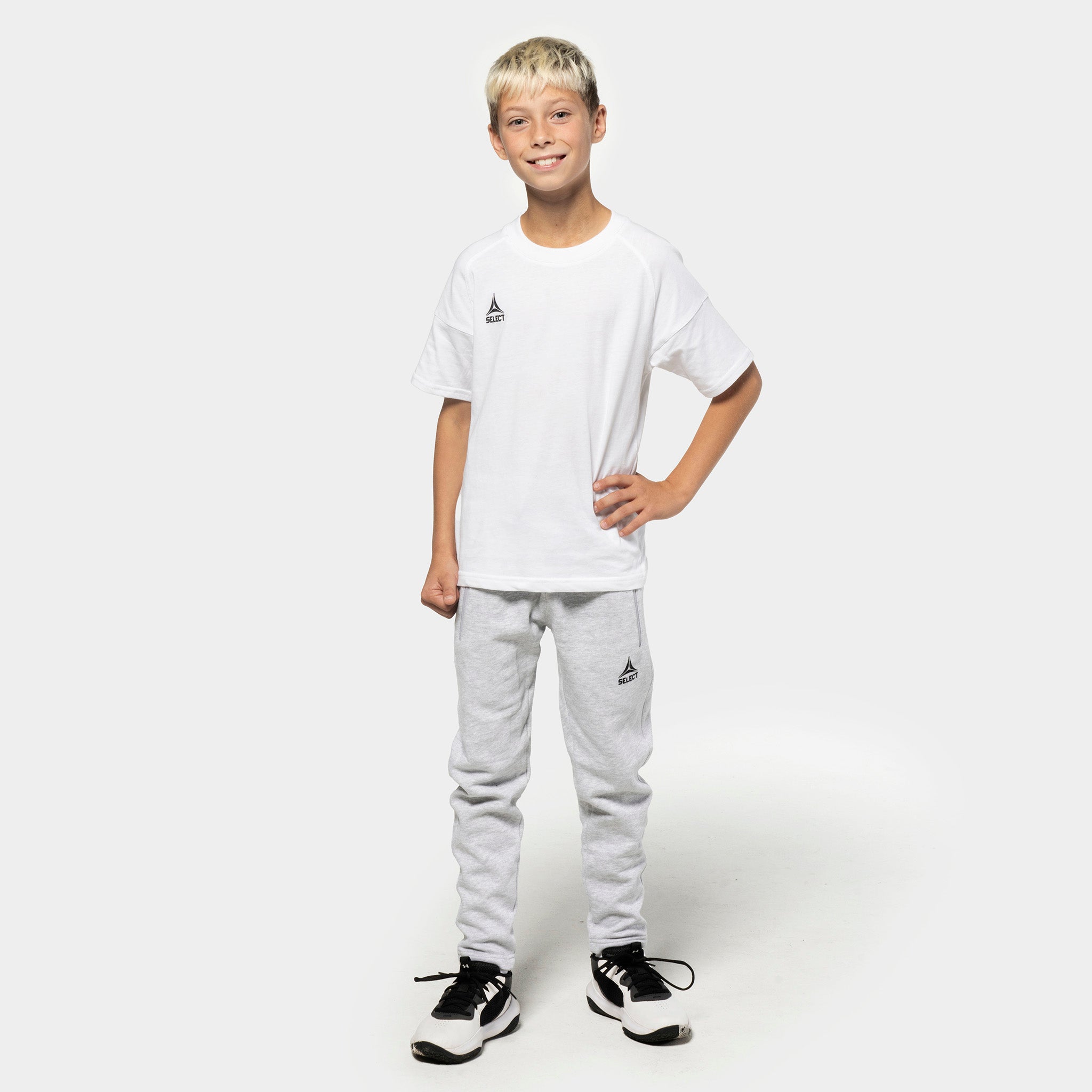 Dreng fodboldspiller i hvid t-shirt og grå Sweat pants Oxford v25, fritidstøj, set forfra.