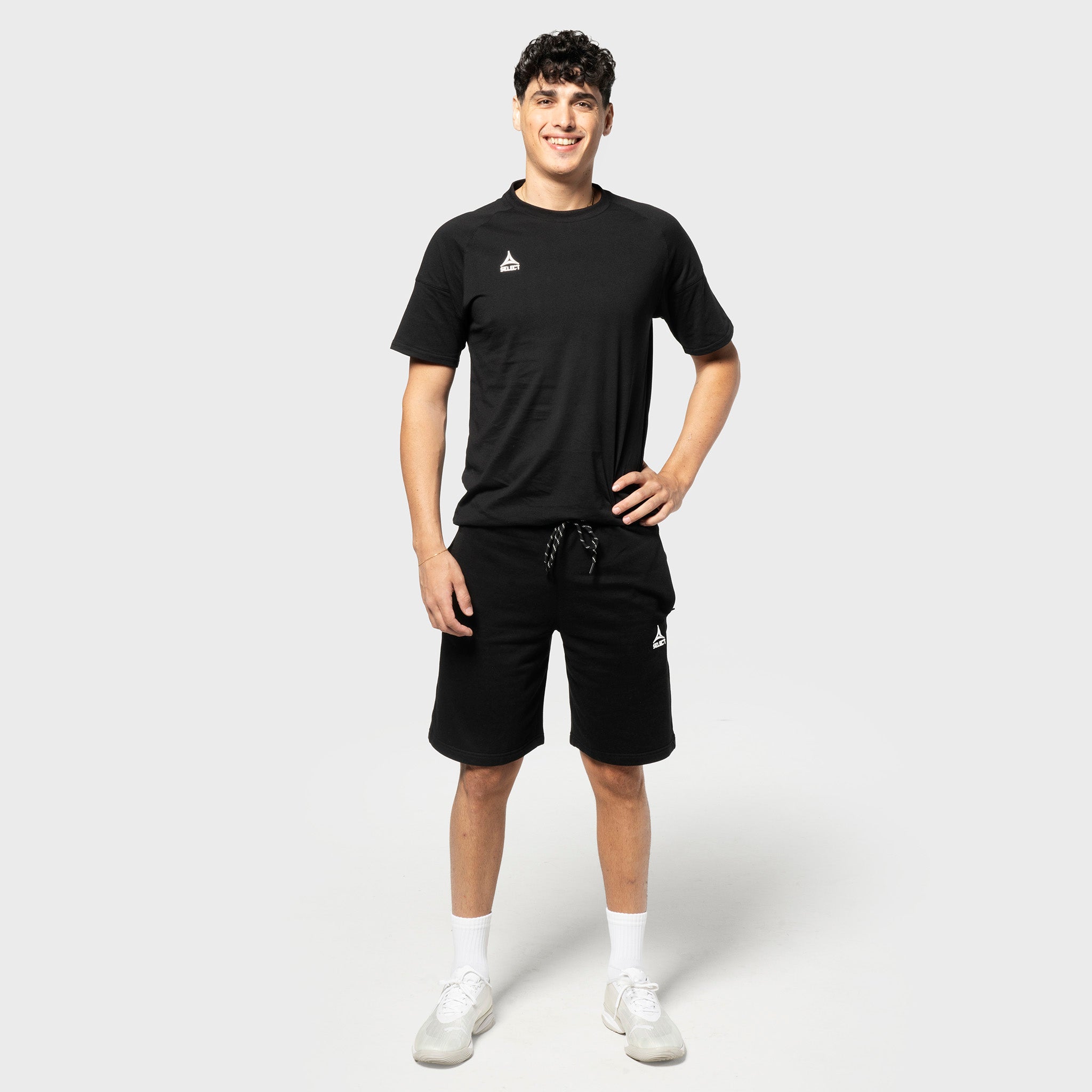 Mandlig fodboldspiller i sorte Sweat shorts Oxford v25 og sort t-shirt, fritidstøj, set forfra.