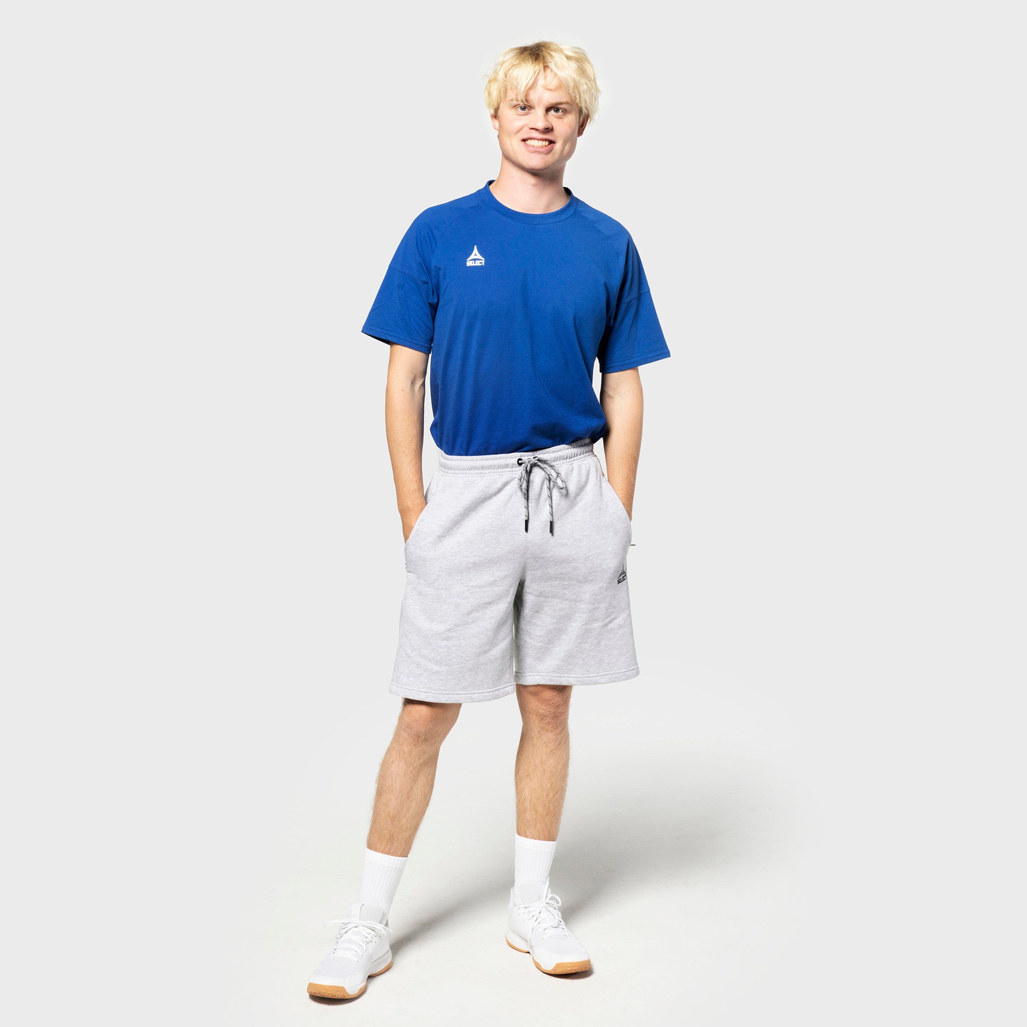 Mandlig fodboldspiller i blå t-shirt og grå Sweat shorts Oxford v25, fritidstøj, forfra.
