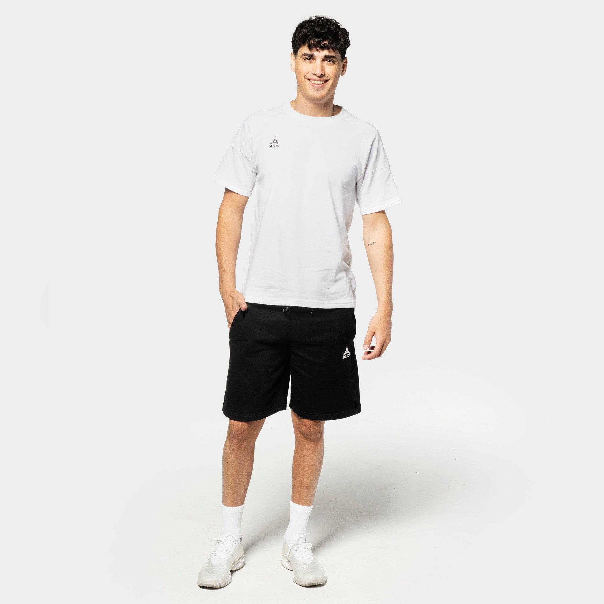 Mandlig fodboldspiller i hvid t-shirt og sorte Sweat shorts Oxford v25, fritidstøj, set forfra.