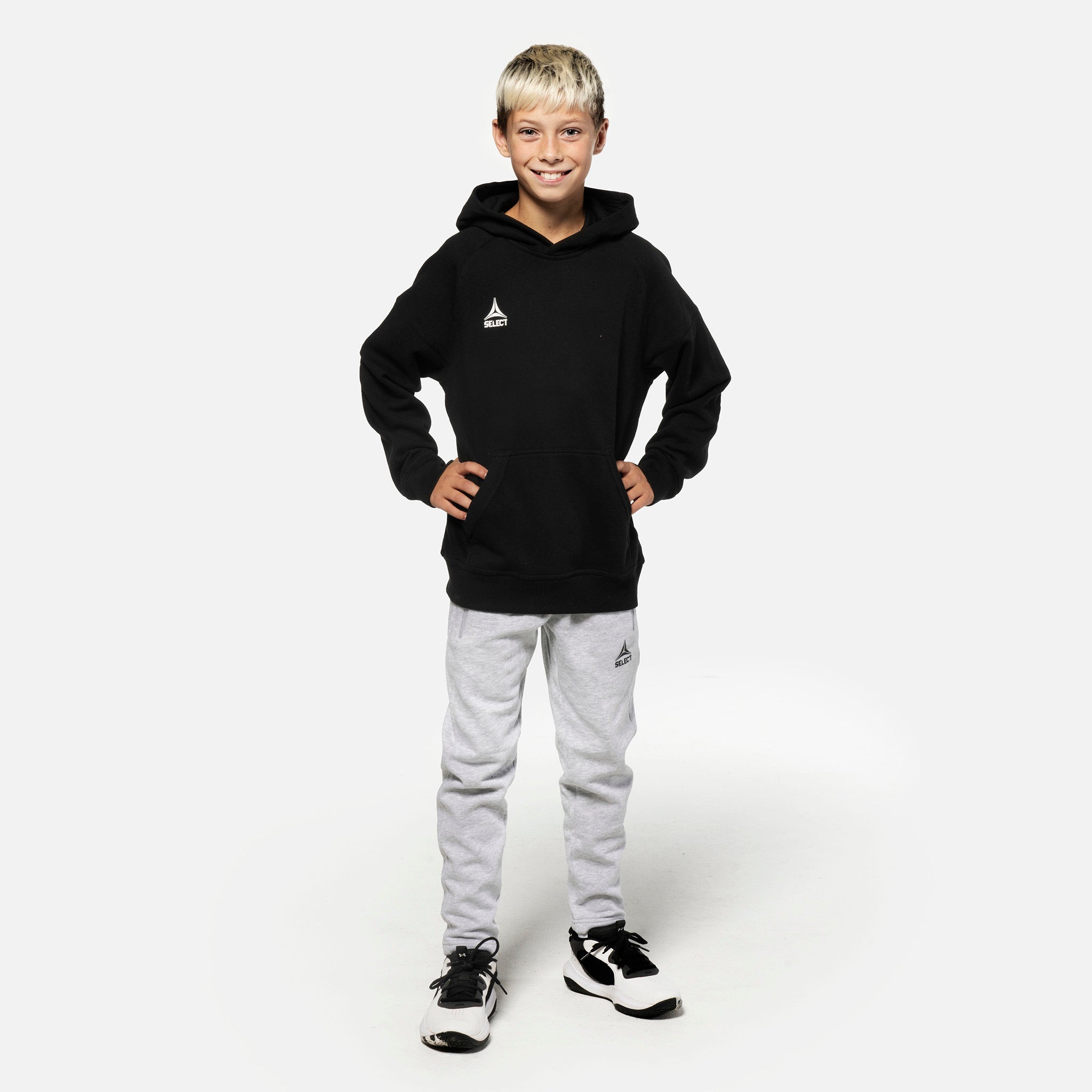 Dreng fodboldspiller i grå Sweat pants Oxford v25 og sort hættetrøje, fritidstøj, set forfra.