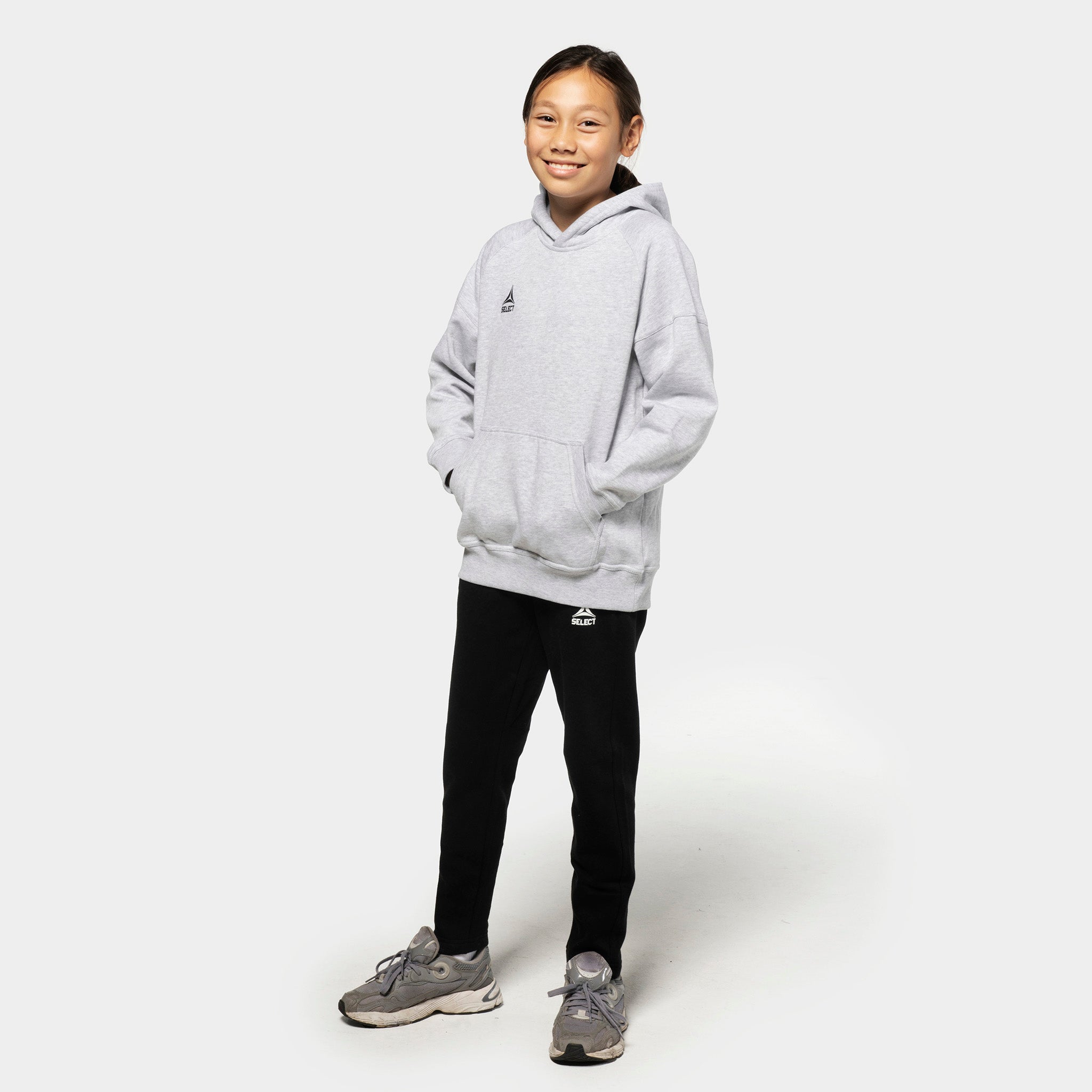 Pige fodboldspiller i grå Oxford v25 hættetrøje og sorte Sweat pants Oxford v25 fritidstøj, set forfra.