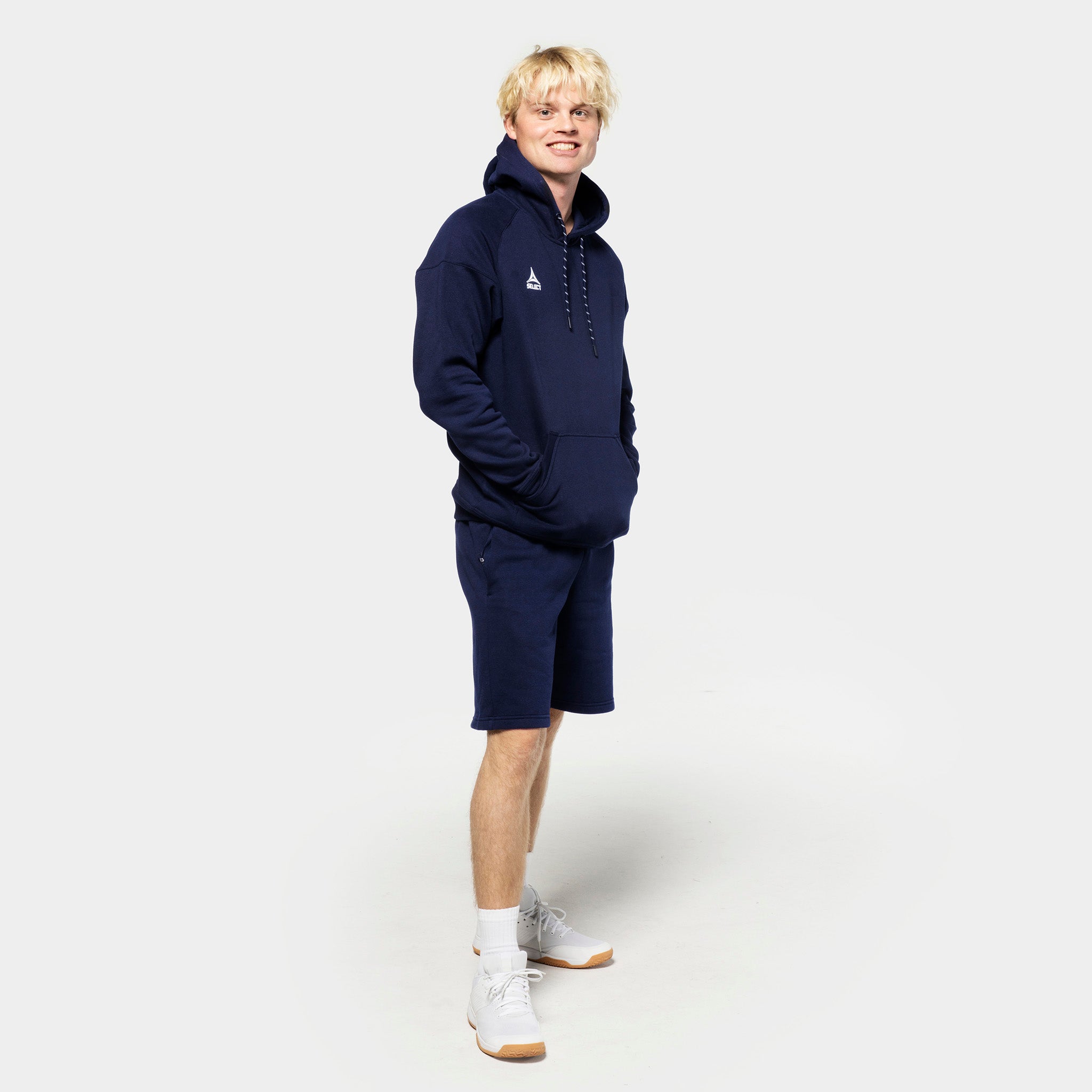 Mandlig fodboldspiller i navy Sweat shorts Oxford v25 og matchende hættetrøje, fritidstøj.