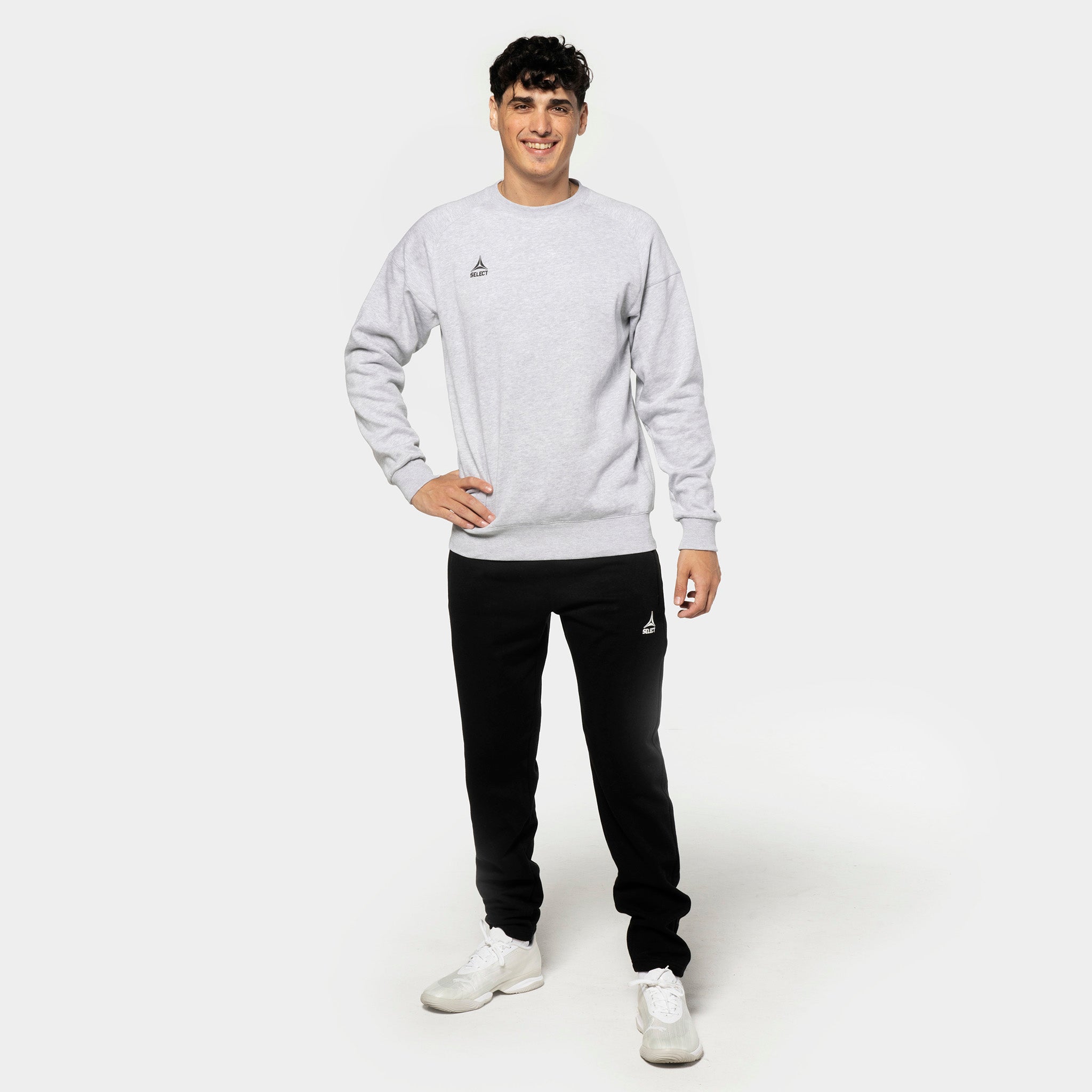 Mandlig fodboldspiller i grå sweatshirt og sorte Sweat pants Oxford v25, fritidstøj, set forfra.
