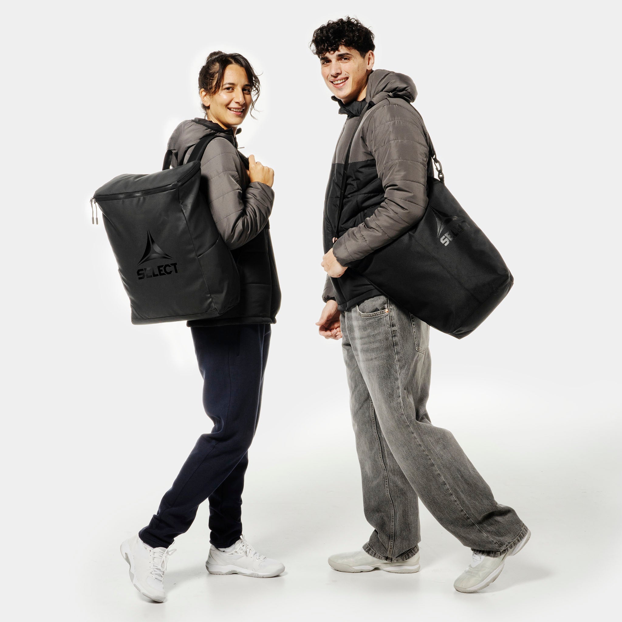 Kvindelig og mandlig fodboldspiller med sorte Crossbody v25 sportstasker med hvidt logo.