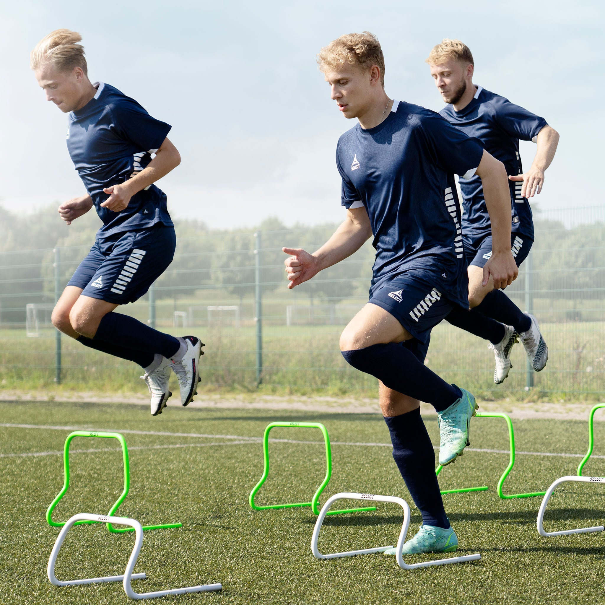 Forsidebillede af fodboldspillere, der bruger grøn Training hurdle træningsudstyr på en bane.
